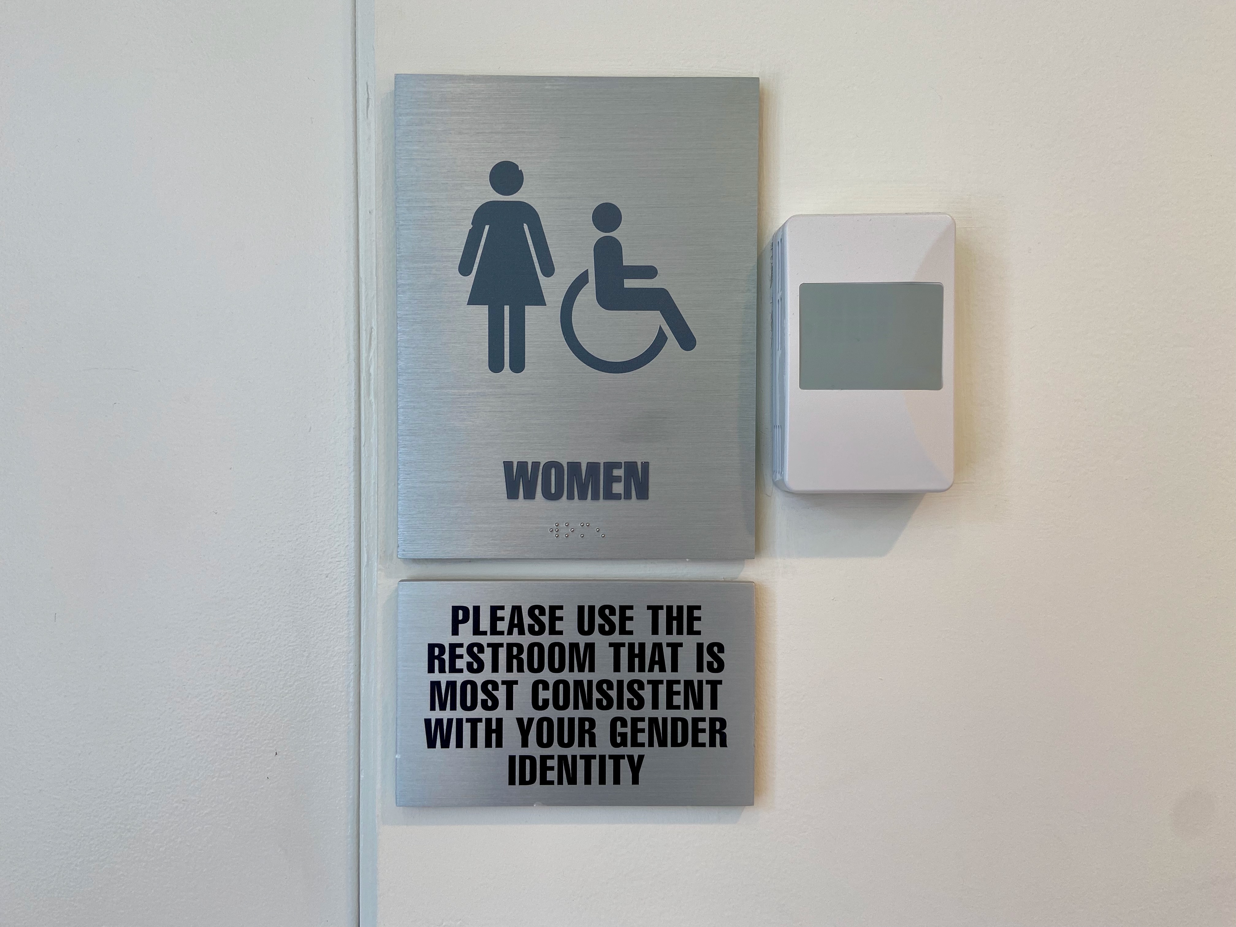 Close-up of women's wheelchair accessible restroom sign that says "Please use the restroom that is most consistent with your gender identity" at Columbia University in New York City